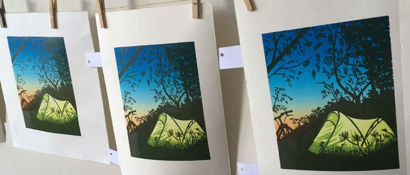 Row of handprinted linoprints hanging to dry. Featuring a tent t night
